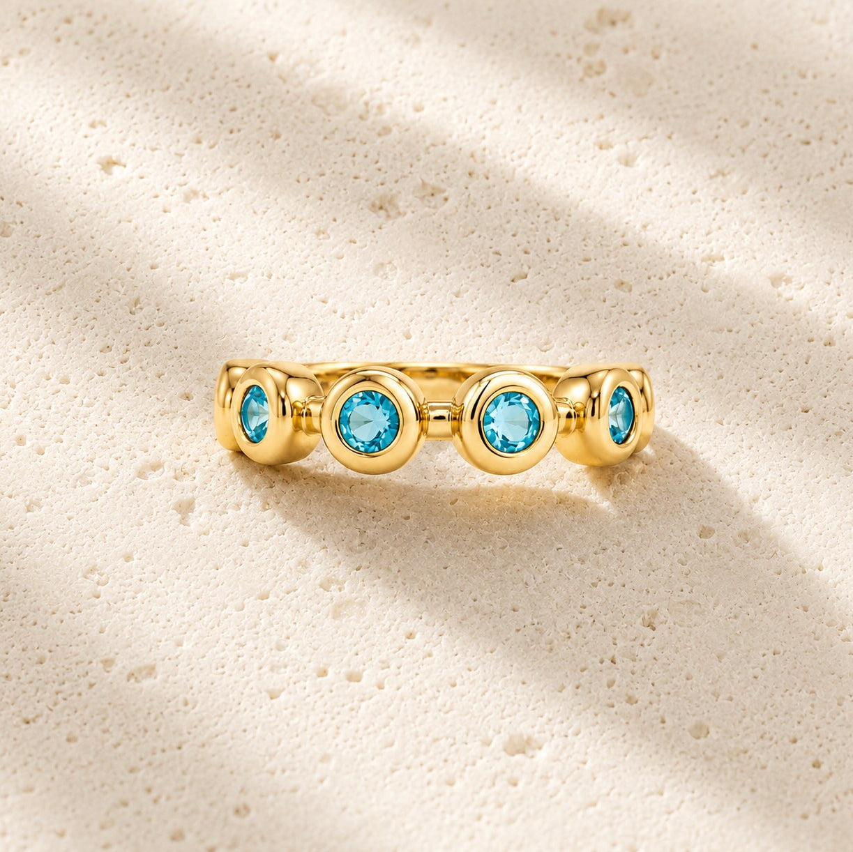 Gold ring with blue gemstones on a beige background