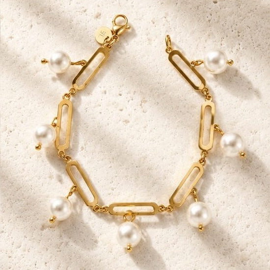 Gold bracelet with pearls on a textured beige surface
