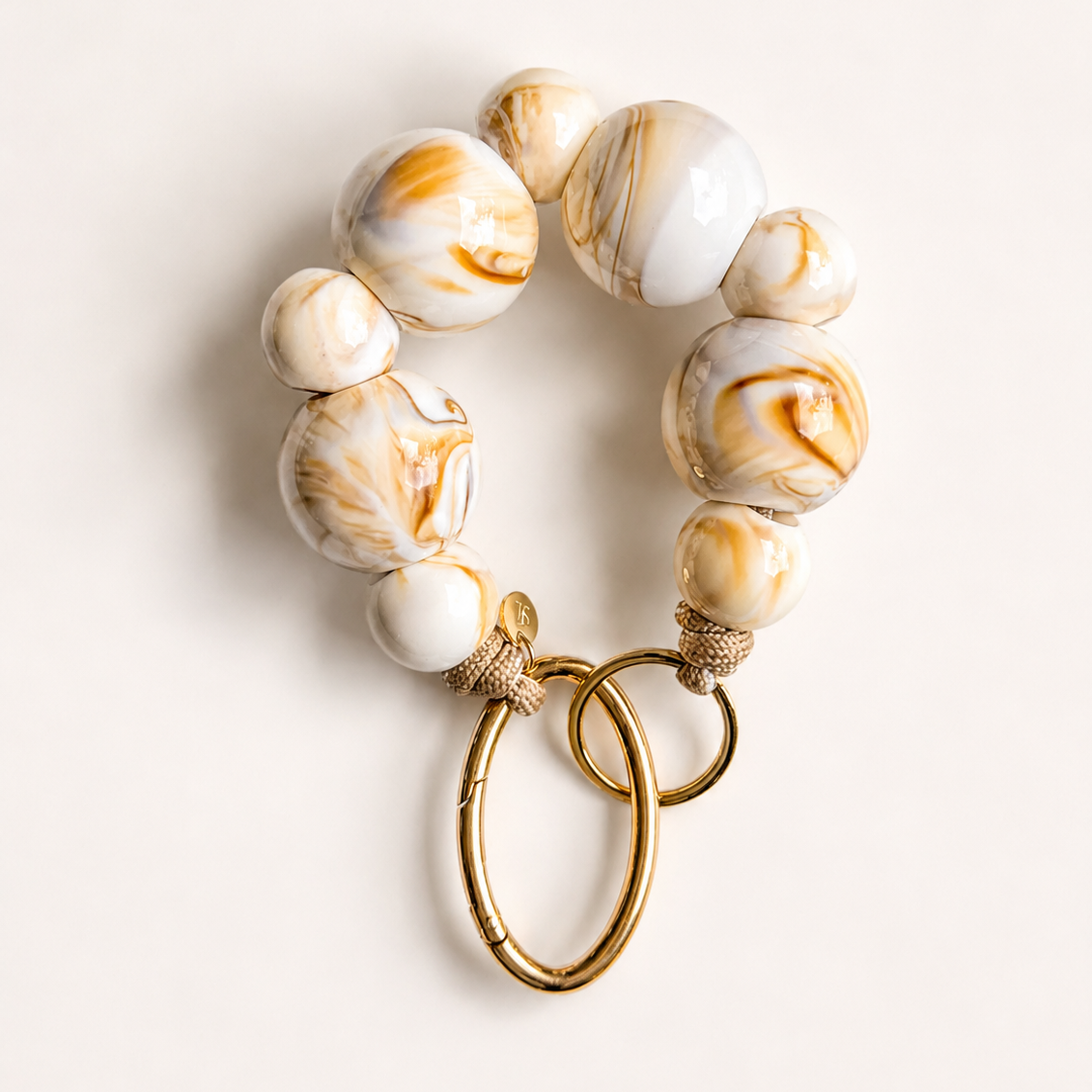 Bracelet with marbled beads and gold clasp on a light background