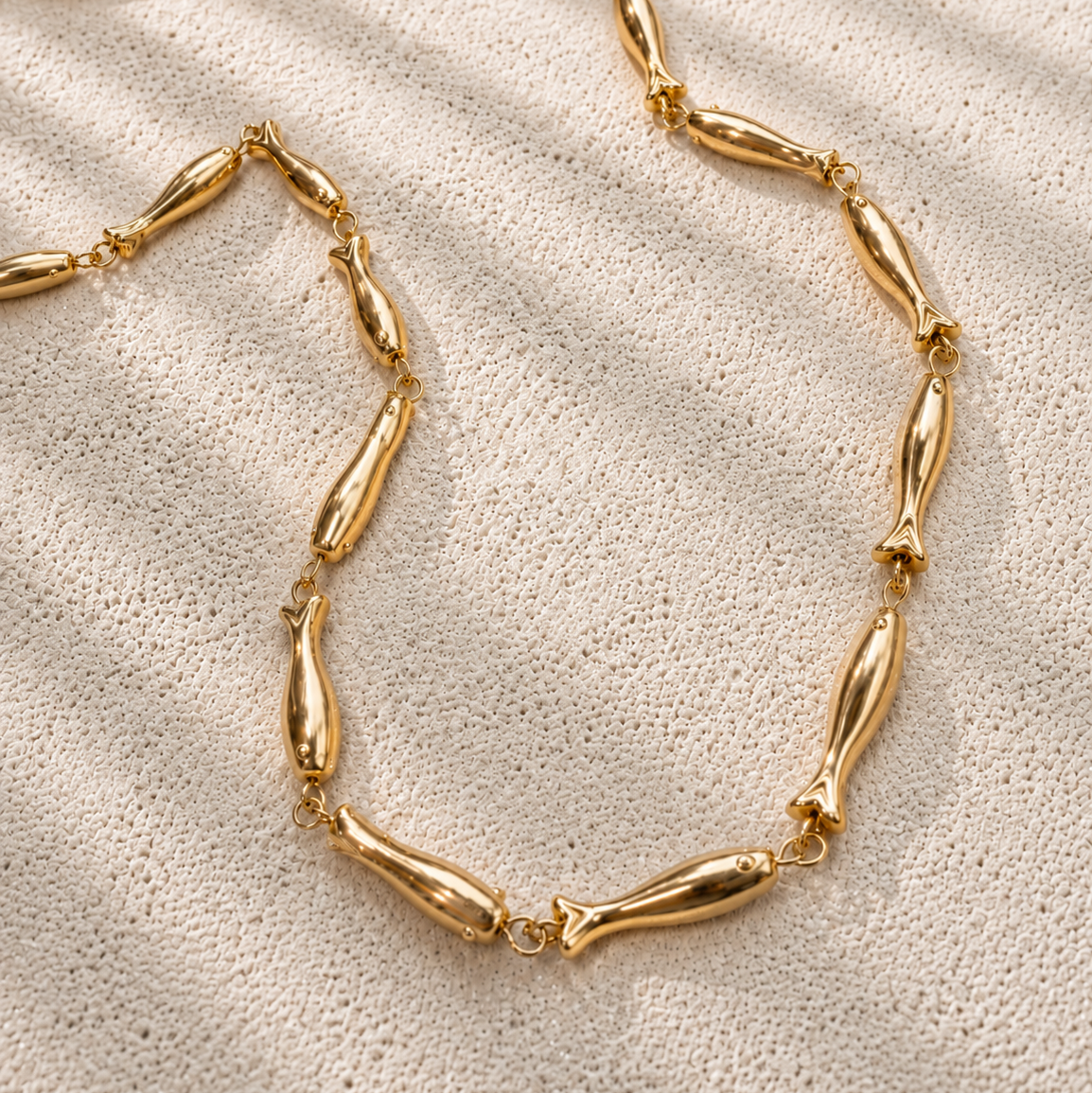 Gold necklace on a textured beige surface