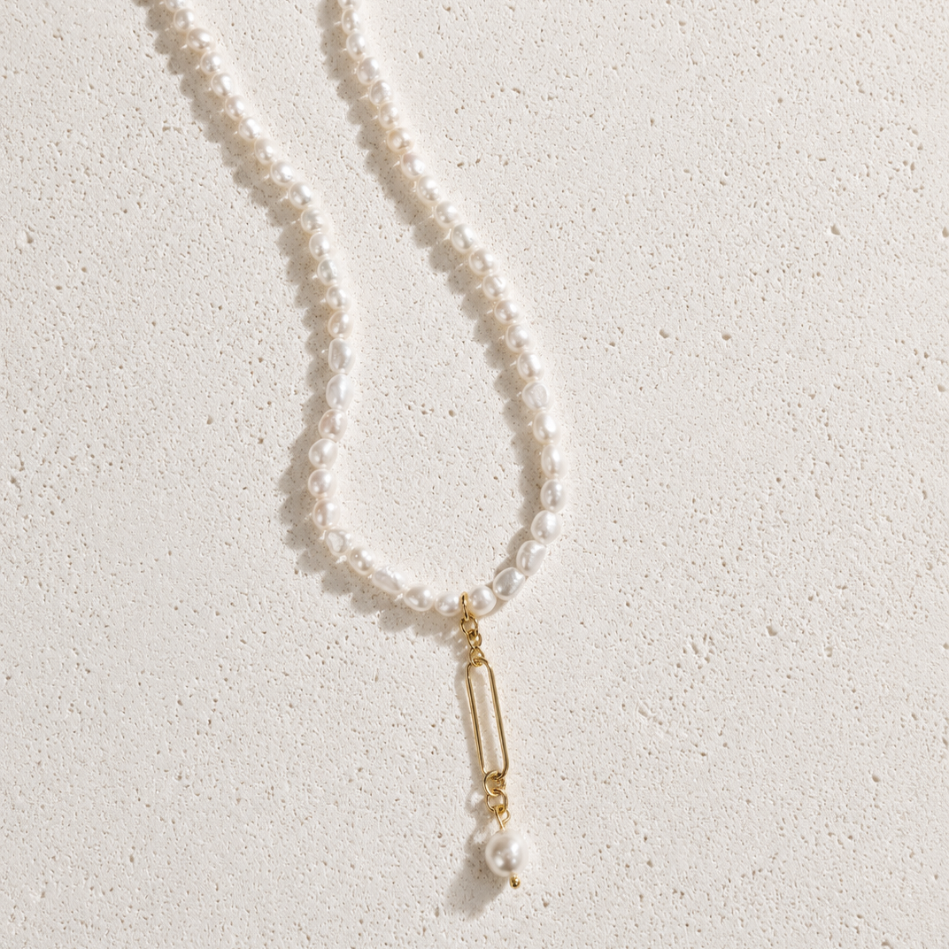 Pearl necklace with a gold pendant on a light background