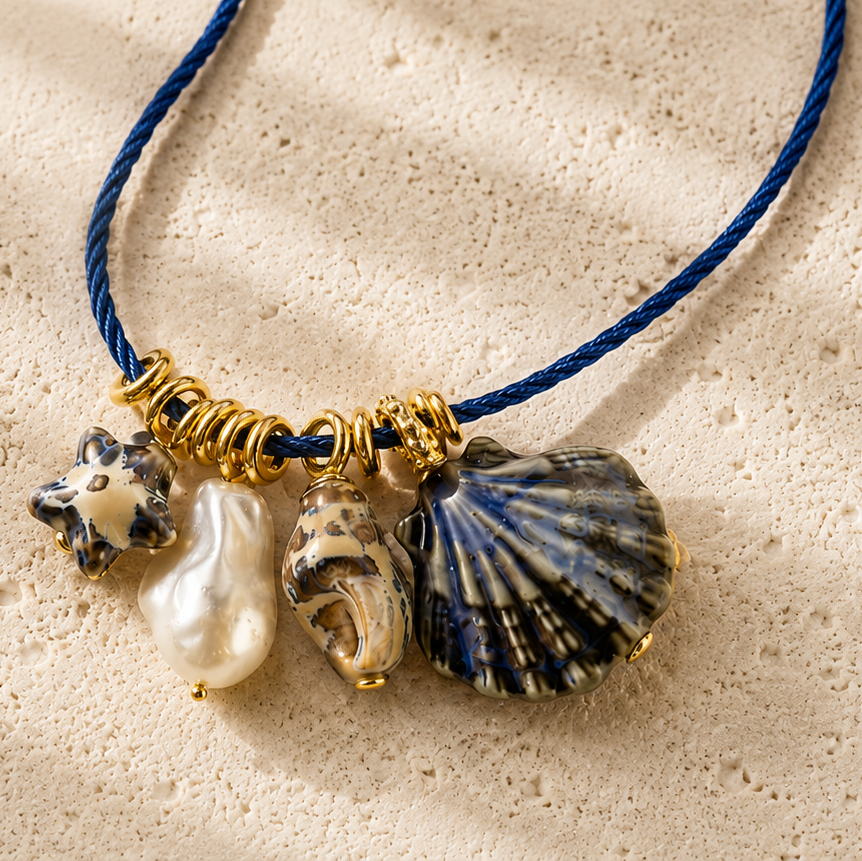 Necklace with shell and pearl charms on a sandy background