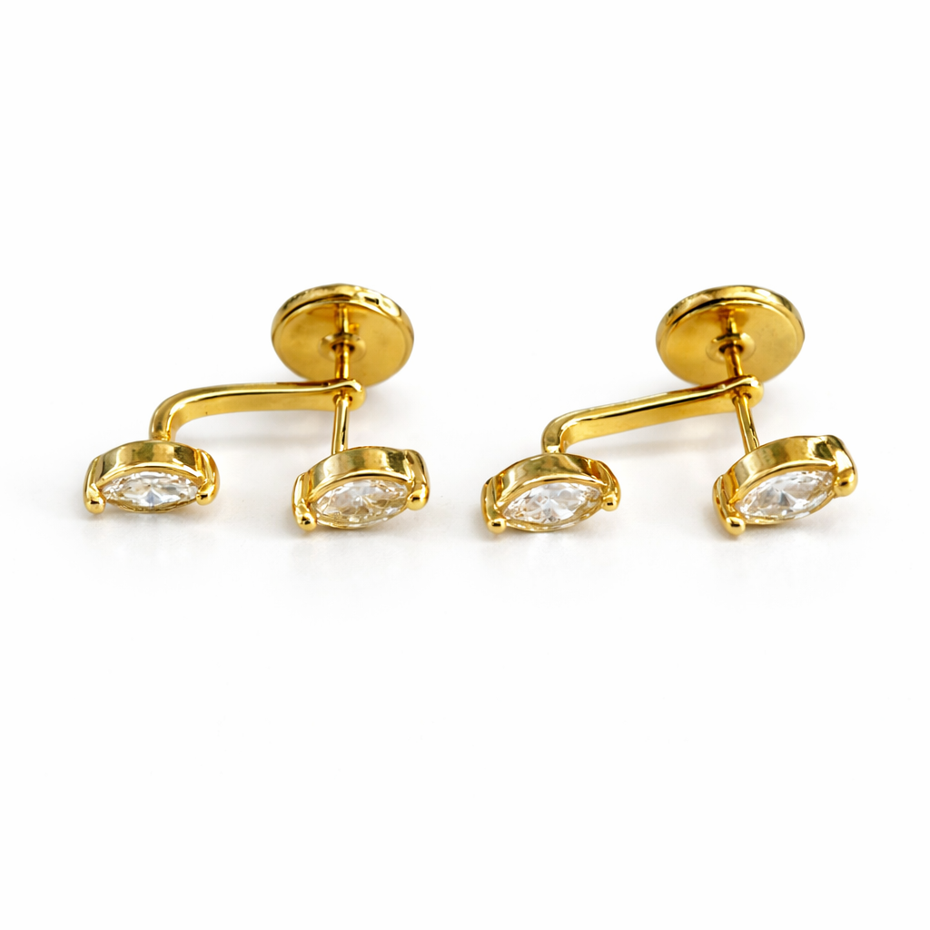Pair of gold earrings with clear gemstones on a white background